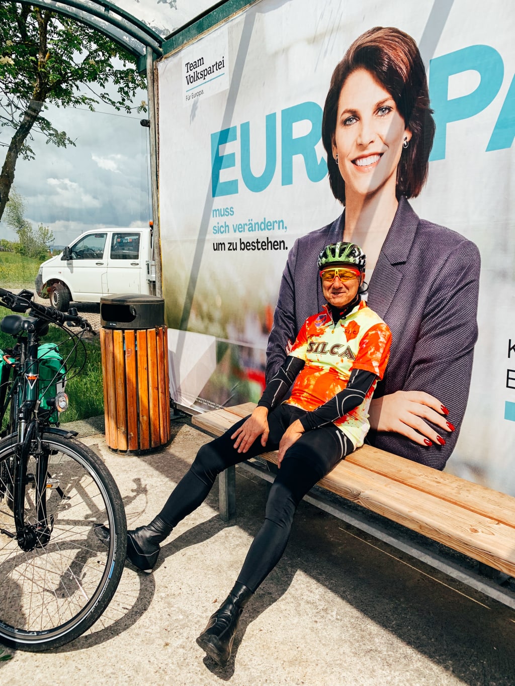 Cicloturista sorridente seduto su una panchina, lungo il percorso ciclabile nel Salzkammergut.